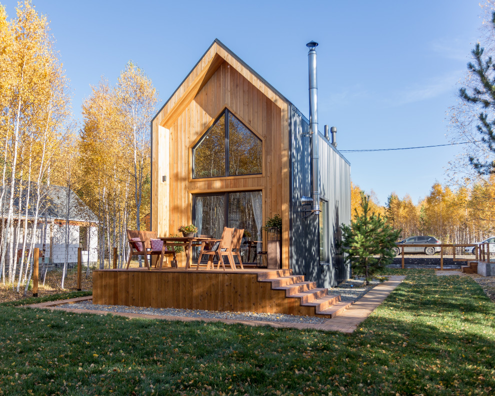 На фото: маленький, двухэтажный, деревянный, коричневый частный загородный дом в скандинавском стиле с двускатной крышей и металлической крышей для на участке и в саду с