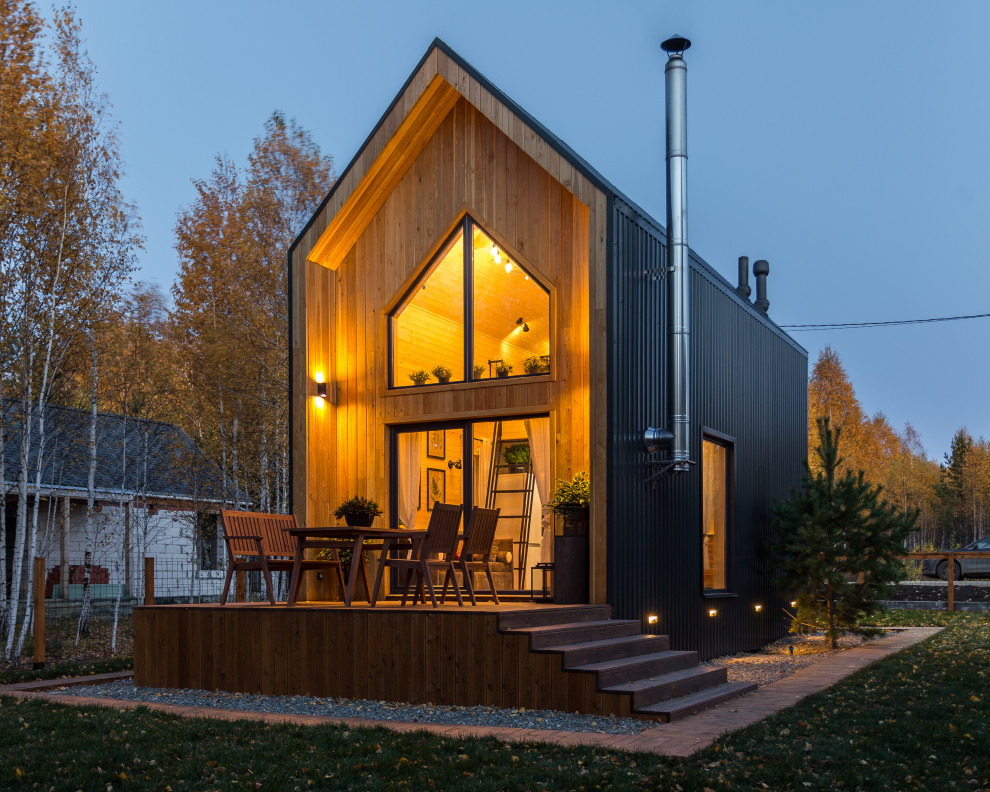 Réalisation d'une petite façade de maison marron nordique en bois à un étage avec un toit à deux pans et un toit en métal.