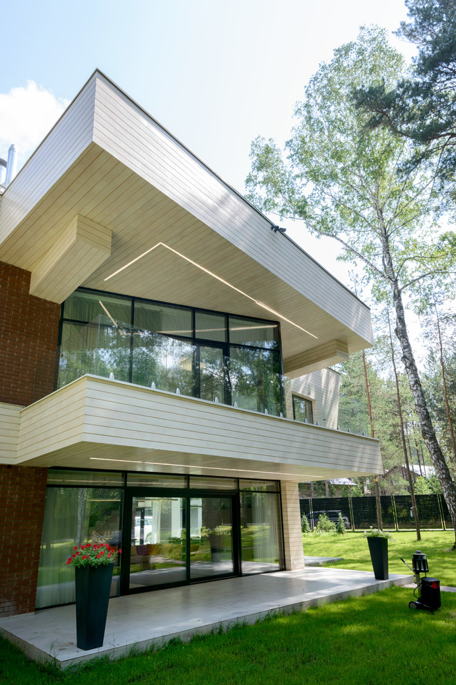 Réalisation d'une façade de maison beige design en bois à deux étages et plus avec un toit plat.