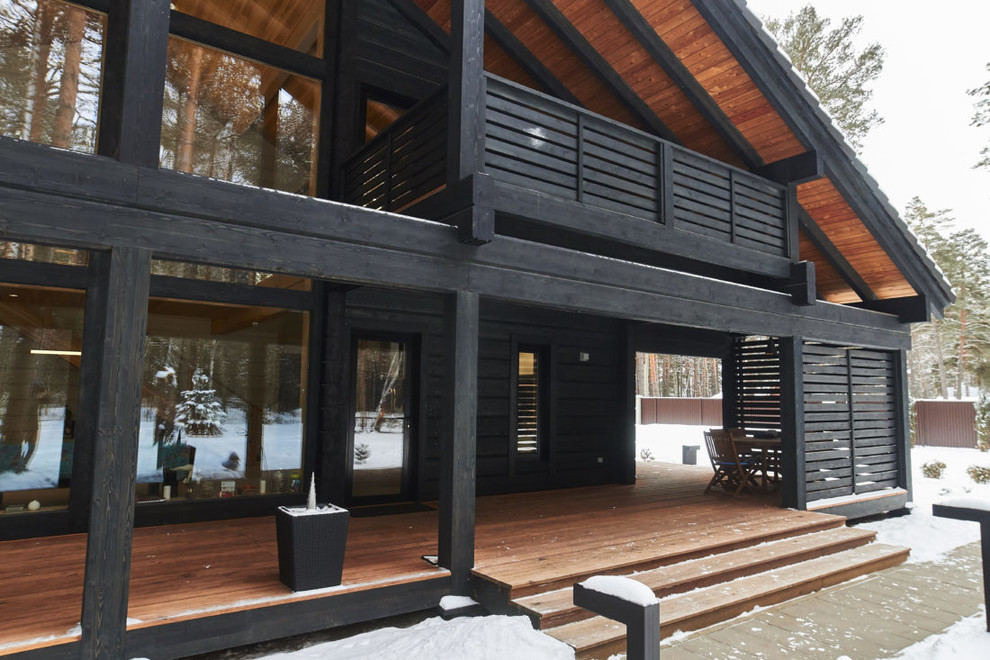 Стильный дизайн: двухэтажный, черный частный загородный дом с двускатной крышей - последний тренд