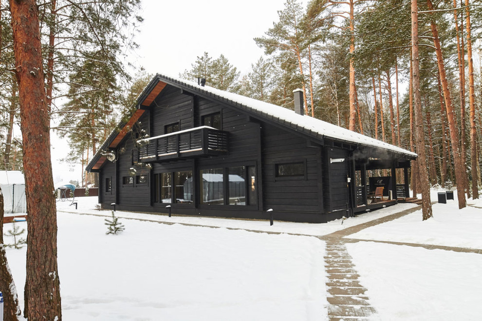 Idée de décoration pour une façade de maison noire à un étage avec un toit à deux pans.