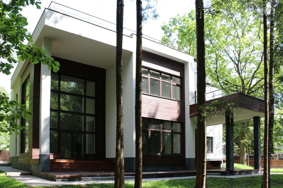 На фото: огромный, двухэтажный, белый частный загородный дом в современном стиле с комбинированной облицовкой, плоской крышей и крышей из смешанных материалов