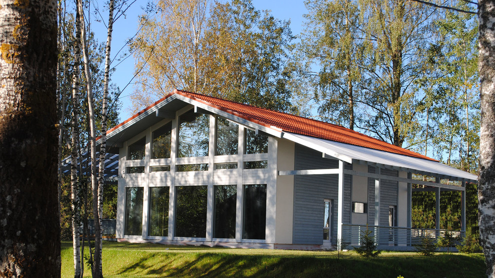 Réalisation d'une façade de maison nordique en verre de taille moyenne et à un étage avec un toit à deux pans et un toit en tuile.