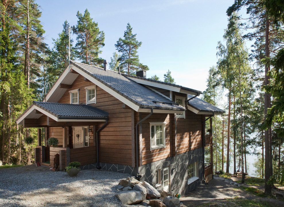 На фото: двухэтажный, деревянный, коричневый частный загородный дом в стиле рустика с двускатной крышей