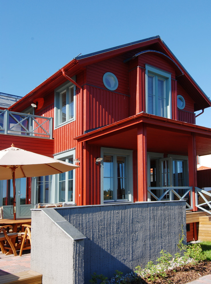 Ejemplo de fachada de casa roja costera de dos plantas con revestimiento de madera, tejado a dos aguas y tejado de metal