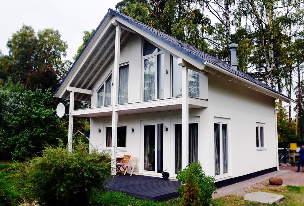Esempio della villa piccola bianca scandinava a due piani con rivestimenti misti, tetto a capanna e copertura in tegole