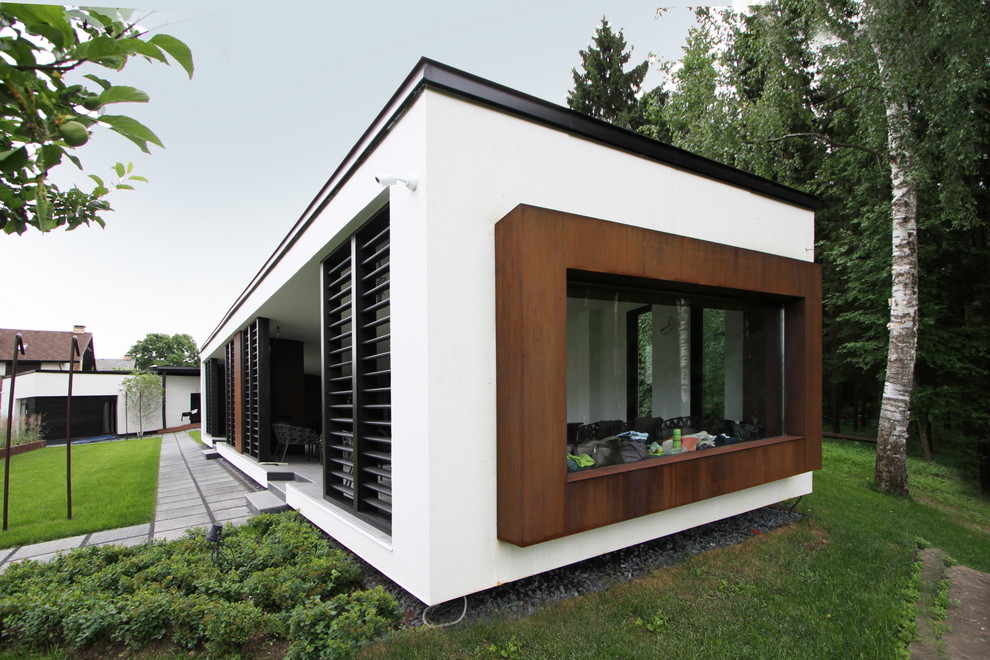 На фото: одноэтажный, белый частный загородный дом среднего размера в современном стиле с облицовкой из металла, плоской крышей и металлической крышей