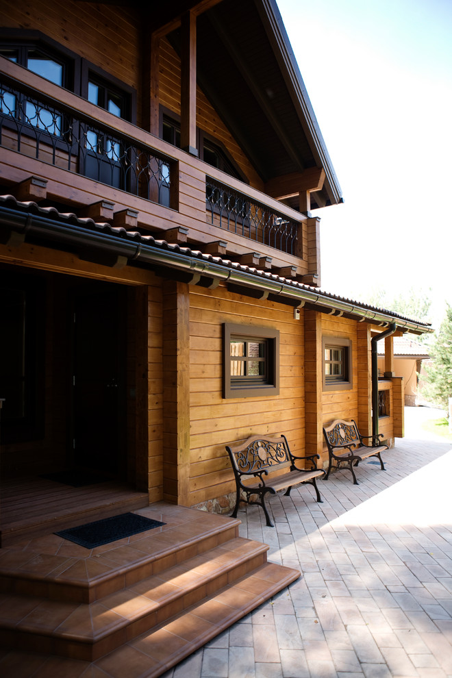 На фото: большой, двухэтажный, деревянный, коричневый частный загородный дом в стиле кантри с черепичной крышей с
