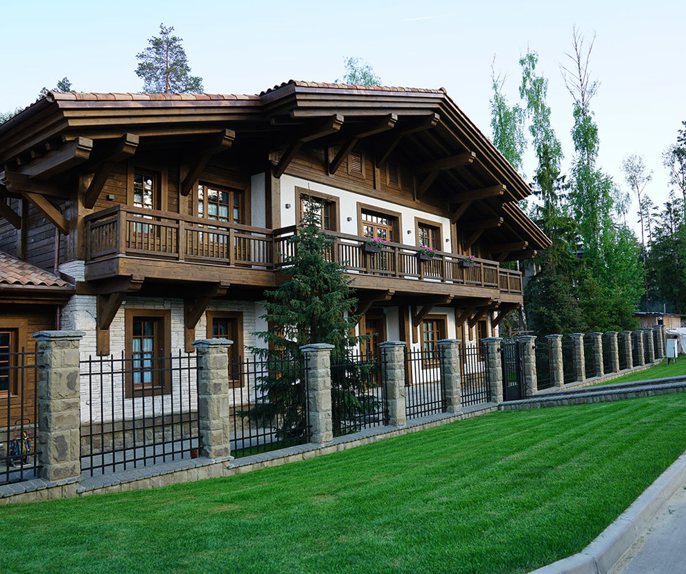 Пример оригинального дизайна: большой, двухэтажный, белый частный загородный дом в стиле рустика с комбинированной облицовкой, двускатной крышей и черепичной крышей