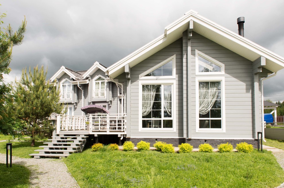 На фото: двухэтажный, деревянный, серый частный загородный дом в классическом стиле с двускатной крышей с