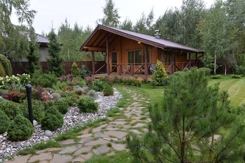 На фото: одноэтажный, деревянный, коричневый частный загородный дом в стиле рустика с двускатной крышей и черепичной крышей