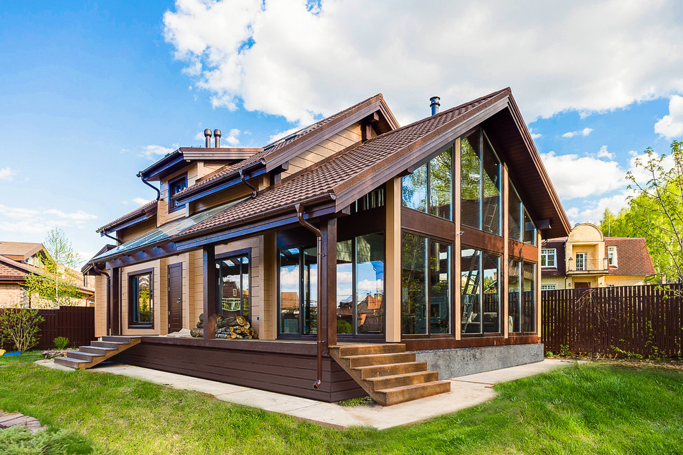 Idée de décoration pour une façade de maison marron chalet en bois à un étage avec un toit à deux pans et un toit en tuile.
