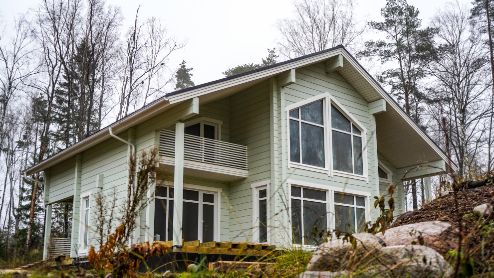 Exemple d'une façade de maison verte scandinave en bois de taille moyenne et à un étage avec un toit à deux pans et un toit en shingle.