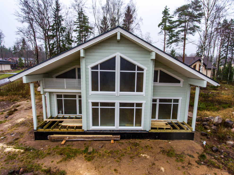 Foto della villa verde scandinava a due piani di medie dimensioni con rivestimento in legno, tetto a capanna e copertura a scandole