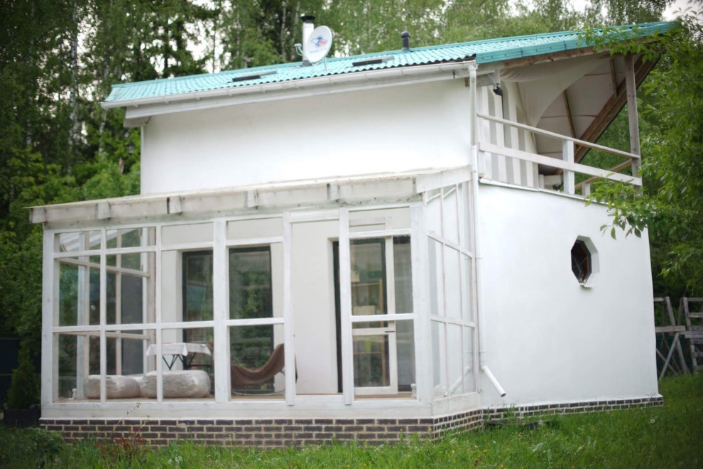 Стильный дизайн: двухэтажный, белый частный загородный дом среднего размера в стиле кантри с облицовкой из самана, двускатной крышей и черепичной крышей - последний тренд