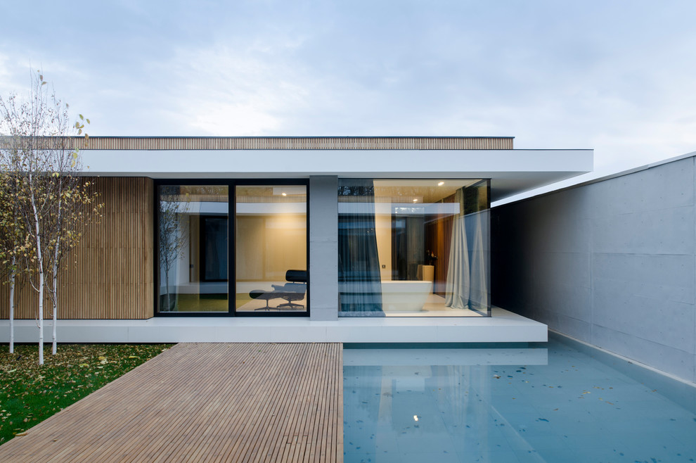 Réalisation d'une façade de maison blanche minimaliste de plain-pied avec un revêtement mixte et un toit plat.