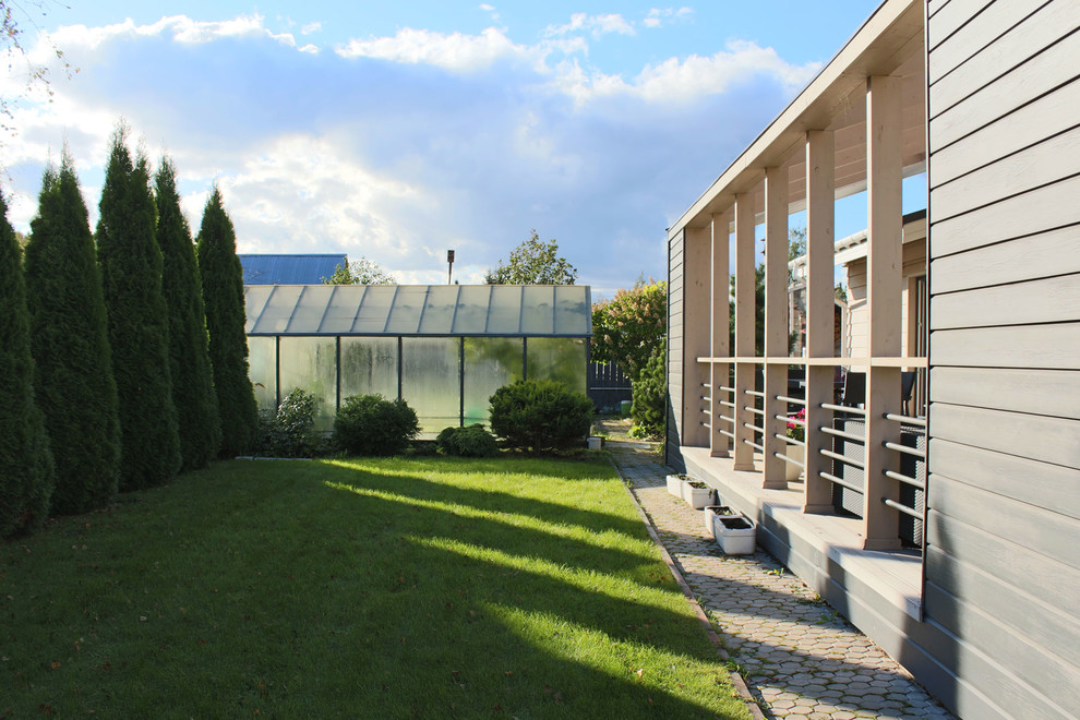 Ejemplo de fachada de casa beige actual de tamaño medio de una planta con revestimiento de vinilo, tejado a dos aguas y tejado de metal