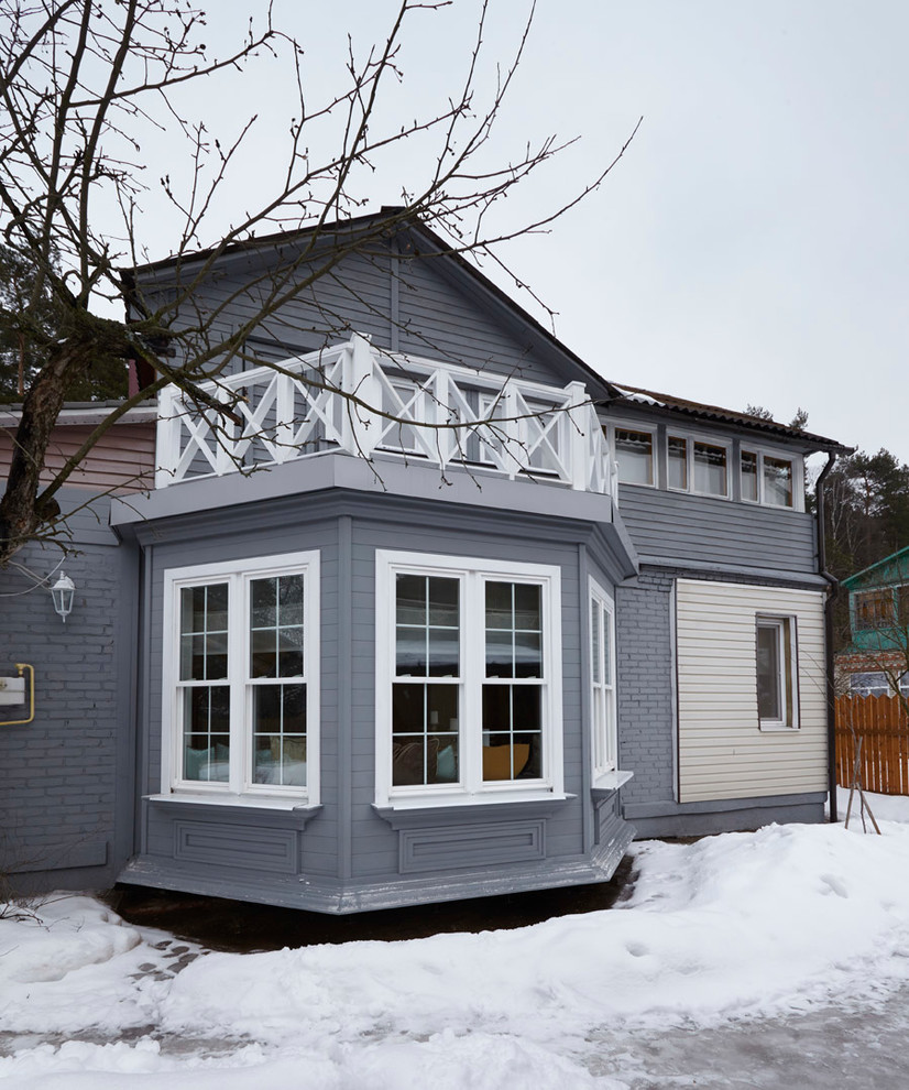 Cette image montre une façade de maison grise nordique à un étage avec un toit à deux pans et un revêtement mixte.
