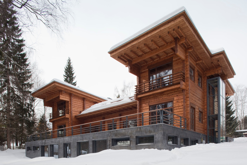Inspiration for a brown contemporary house exterior in Moscow with three floors, wood cladding and a flat roof.