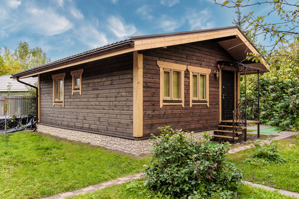 Esempio della villa piccola marrone country a un piano con rivestimento in legno, tetto a capanna e copertura in metallo o lamiera
