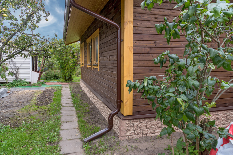 Стильный дизайн: маленький, коричневый частный загородный дом в стиле рустика с двускатной крышей для на участке и в саду - последний тренд