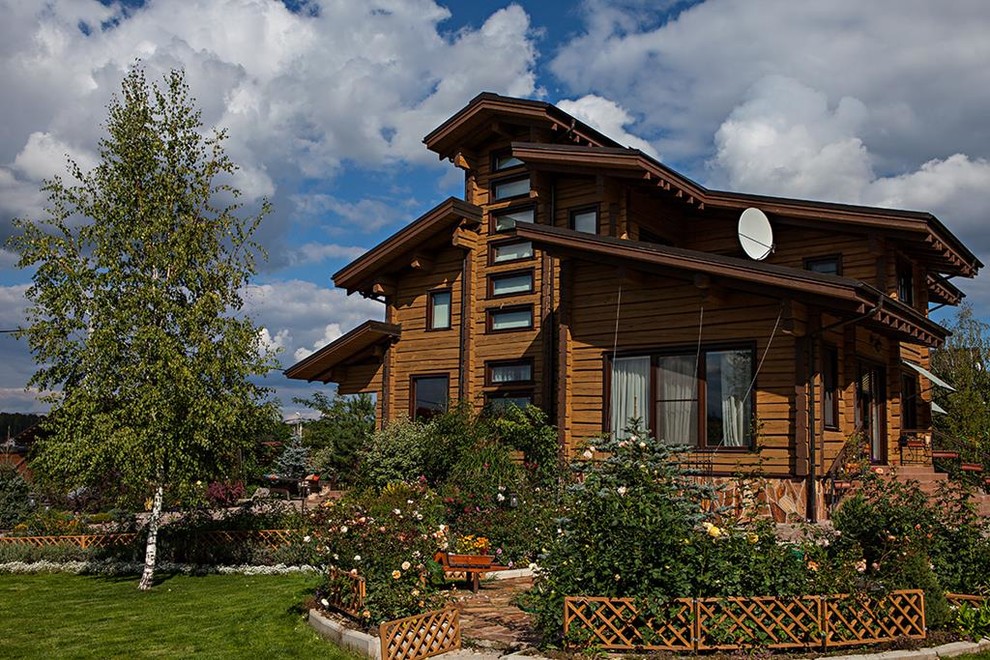 Diseño de fachada de casa marrón campestre grande a niveles con revestimientos combinados, tejado a doble faldón y tejado de teja de madera