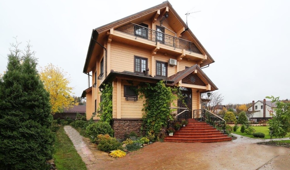 Пример оригинального дизайна: трехэтажный, деревянный, бежевый дом в стиле кантри с двускатной крышей