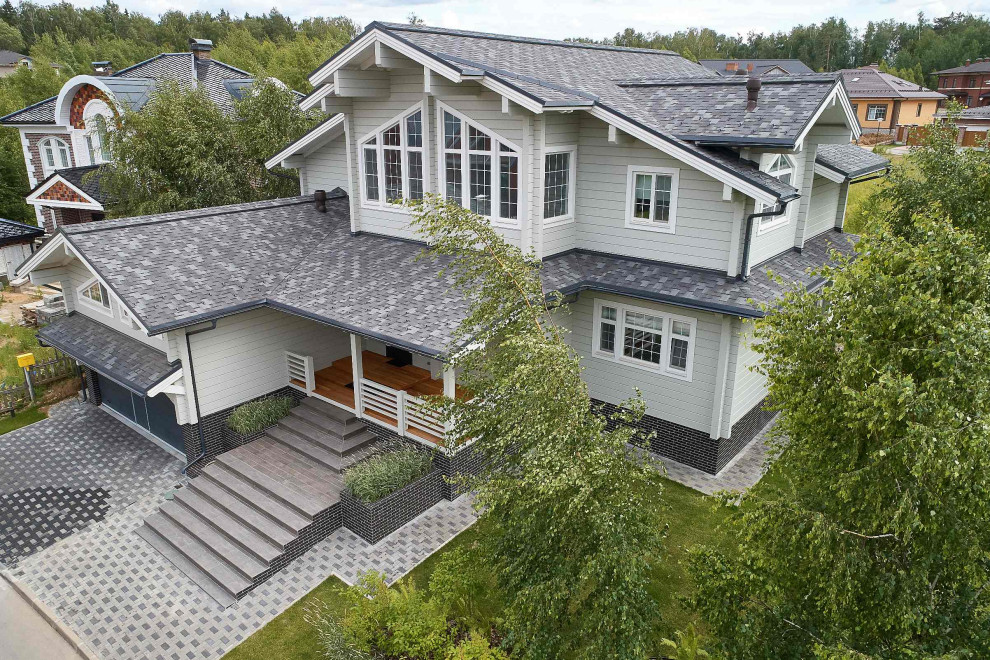 Aménagement d'une grande façade de maison grise en bois à un étage avec un toit à deux pans et un toit en shingle.