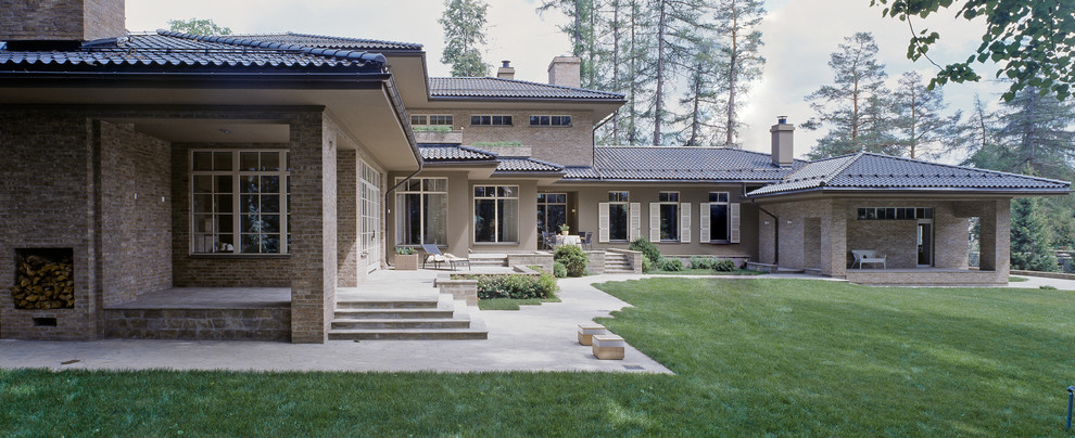 Ejemplo de fachada de casa beige tradicional de dos plantas con revestimiento de ladrillo, tejado a cuatro aguas y tejado de teja de barro