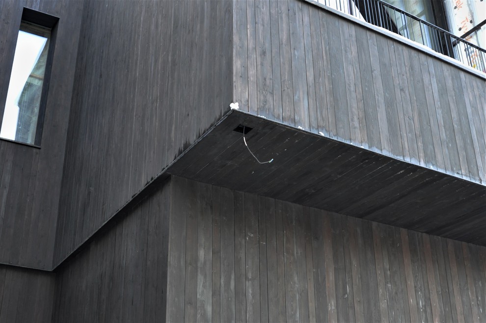 Esempio della facciata di una casa nera contemporanea con rivestimento in legno