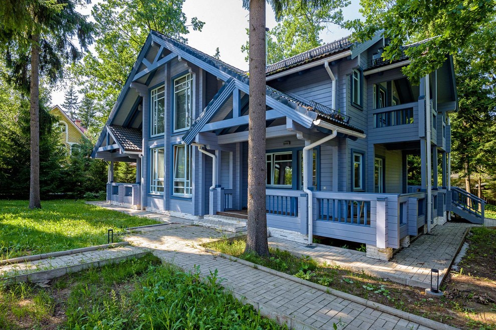 На фото: двухэтажный, деревянный, синий частный загородный дом среднего размера в современном стиле с двускатной крышей и черепичной крышей