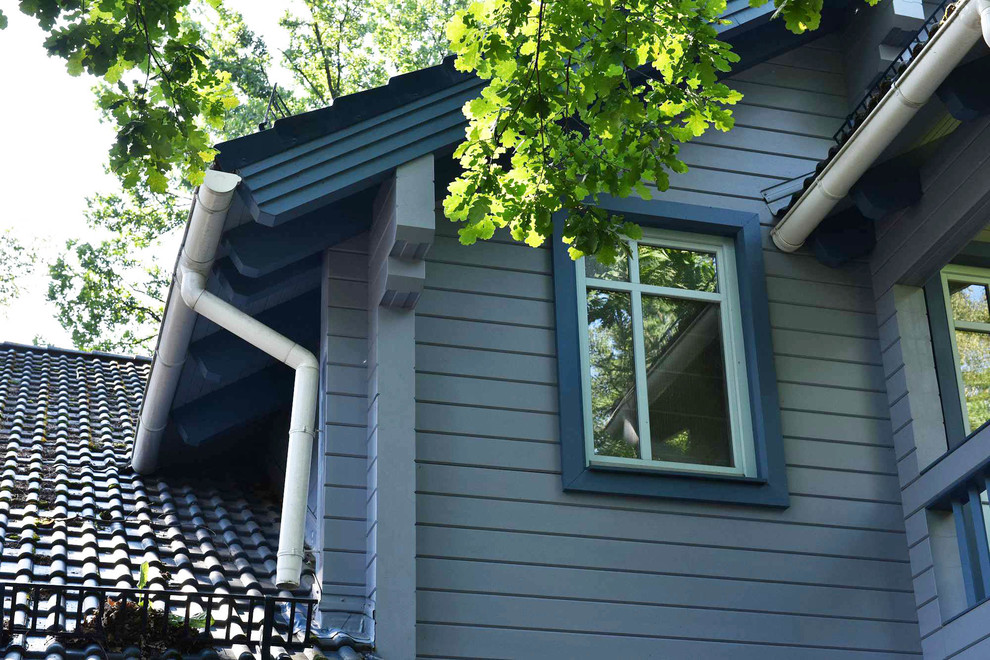 Стильный дизайн: двухэтажный, деревянный, синий частный загородный дом среднего размера в стиле неоклассика (современная классика) с двускатной крышей и черепичной крышей - последний тренд