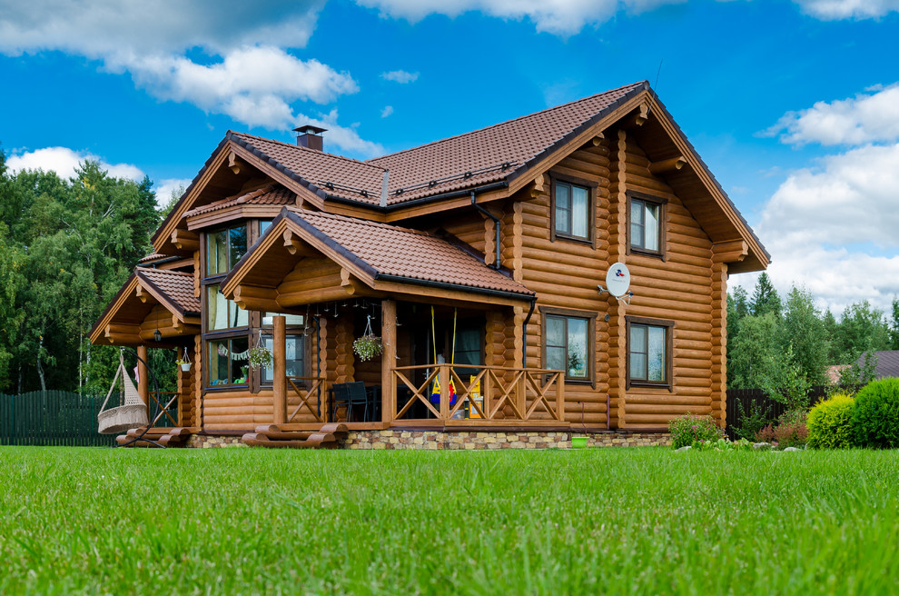 На фото: двухэтажный, деревянный, коричневый частный загородный дом среднего размера в классическом стиле с двускатной крышей и черепичной крышей с