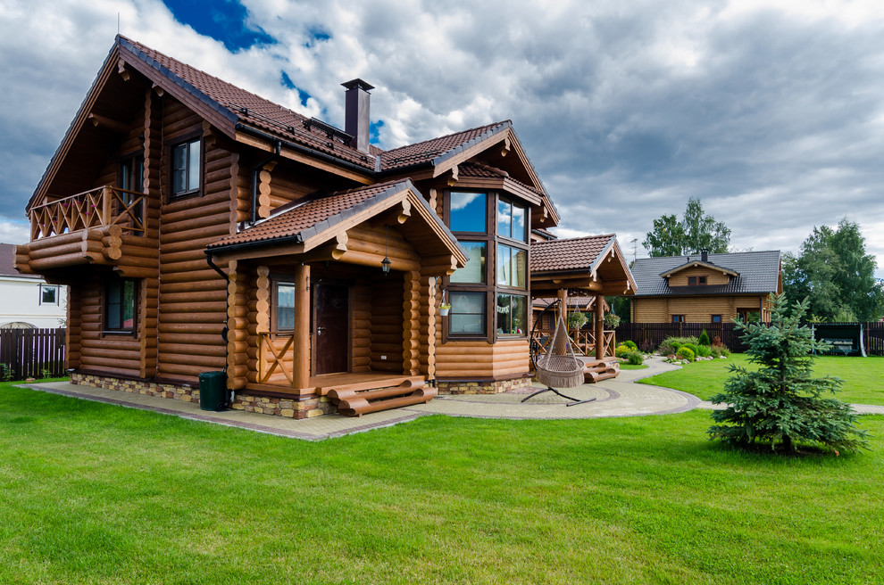 Medium sized and brown traditional two floor detached house in Saint Petersburg with wood cladding, a pitched roof and a tiled roof.