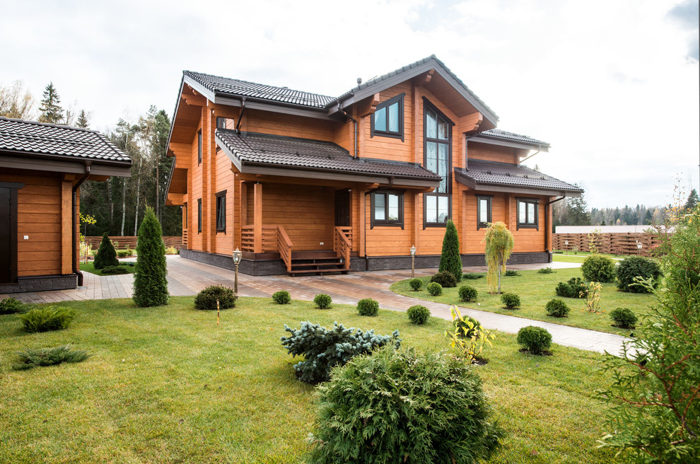 Mid-sized farmhouse brown two-story wood exterior home photo in Moscow with a tile roof