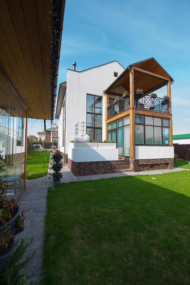 На фото: двухэтажный, белый частный загородный дом среднего размера в современном стиле с облицовкой из цементной штукатурки, двускатной крышей и металлической крышей с