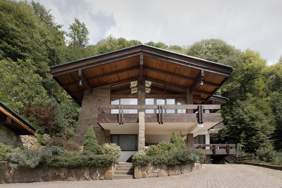 Идея дизайна: двухэтажный, коричневый дом в стиле рустика с облицовкой из камня и двускатной крышей