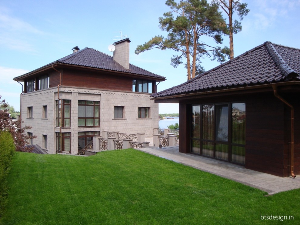 На фото: большой, трехэтажный, коричневый частный загородный дом в стиле неоклассика (современная классика) с облицовкой из камня, мансардной крышей и черепичной крышей