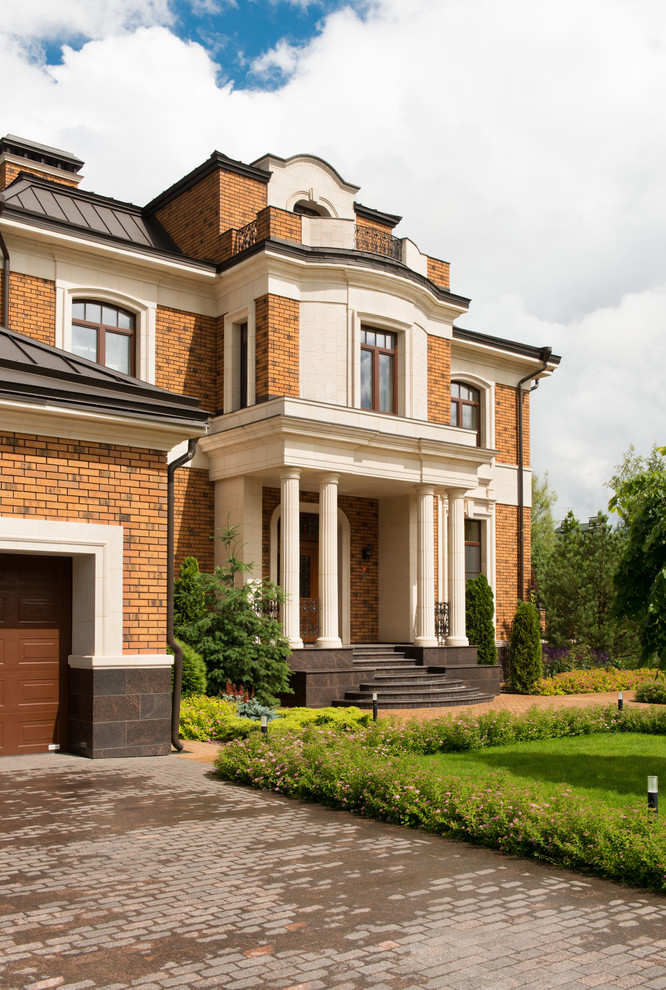 Immagine della villa grande multicolore classica a piani sfalsati con rivestimento in mattoni, tetto a mansarda e copertura in metallo o lamiera
