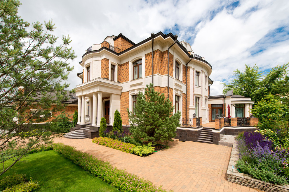 Diseño de fachada de casa multicolor tradicional grande a niveles con revestimiento de ladrillo, tejado a doble faldón y tejado de metal