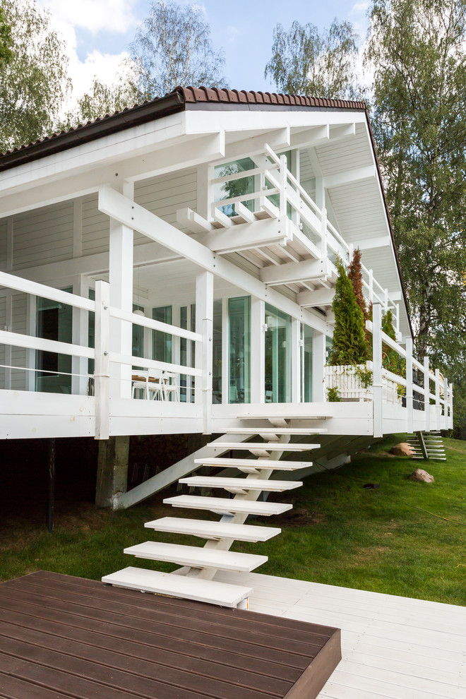 Esempio della facciata di una casa bianca scandinava a due piani con rivestimento in legno e tetto a capanna