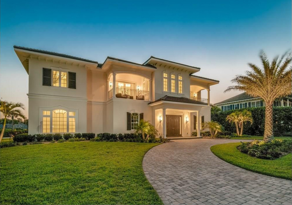 Expansive and beige mediterranean two floor render detached house in Miami with a hip roof and a tiled roof.