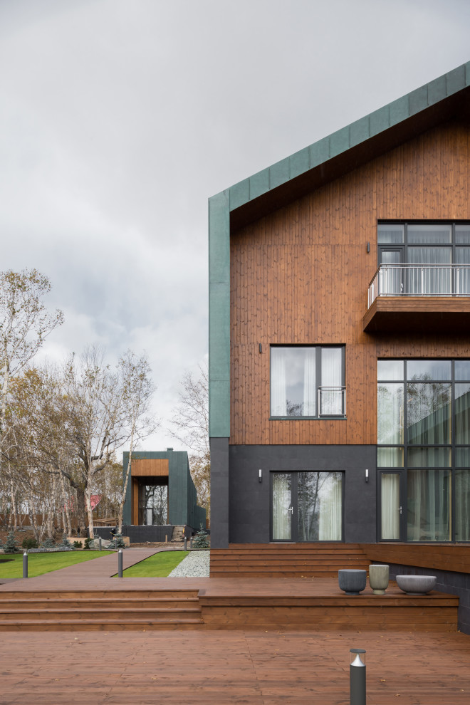 Diseño de fachada de casa multicolor moderna grande de tres plantas con revestimientos combinados, tejado a dos aguas y tejado de metal