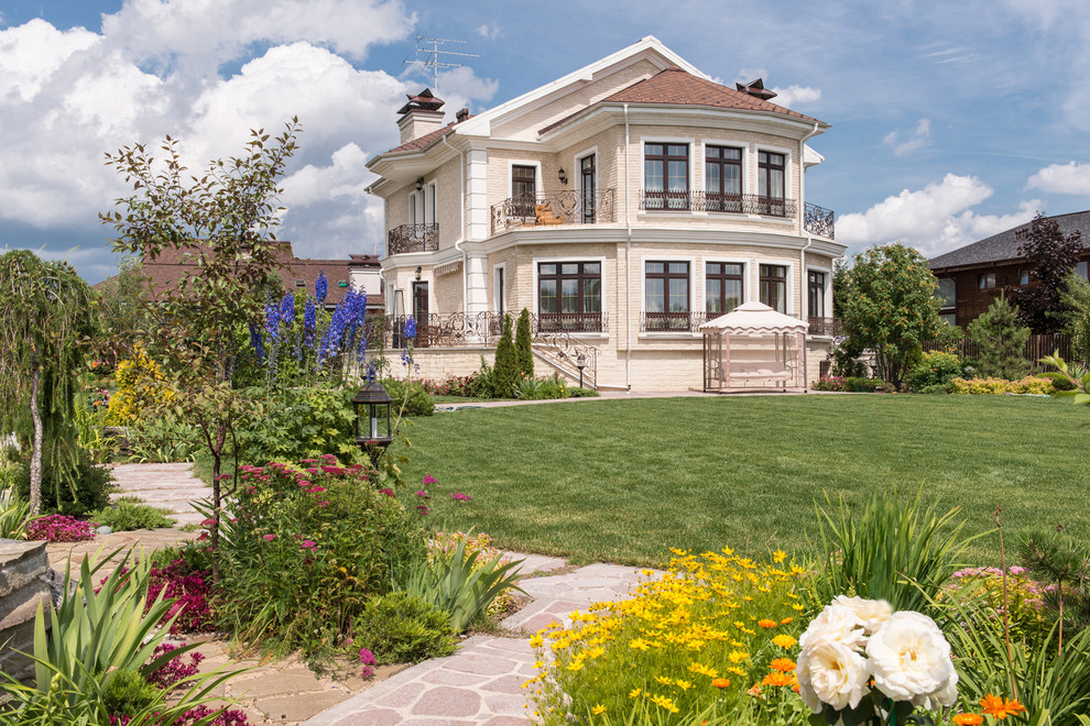 Large and beige classic brick house exterior in Moscow with three floors and a pitched roof.