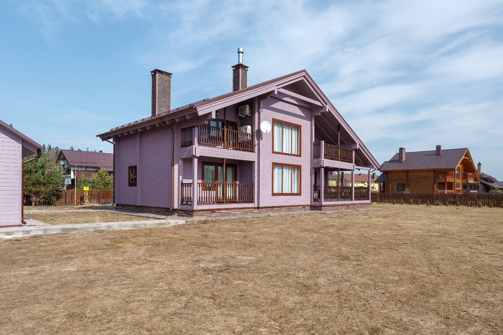 На фото: большой, двухэтажный, деревянный, фиолетовый частный загородный дом с двускатной крышей и металлической крышей с