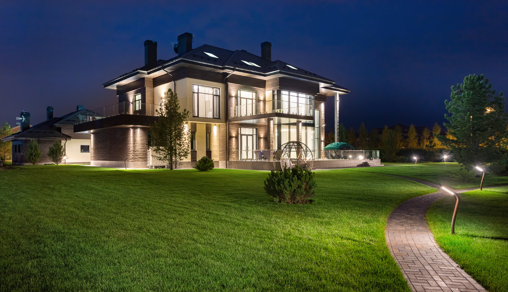 Стильный дизайн: большой, трехэтажный, коричневый частный загородный дом в стиле фьюжн с облицовкой из камня, плоской крышей, черепичной крышей, синей крышей и отделкой доской с нащельником - последний тренд