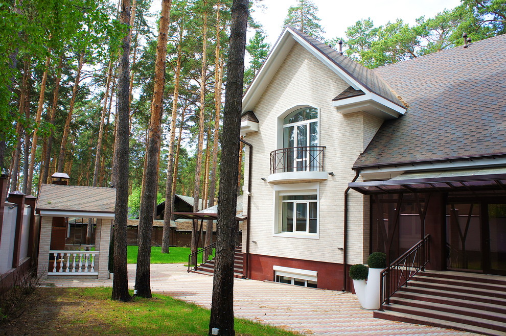 Пример оригинального дизайна: двухэтажный, бежевый частный загородный дом среднего размера в стиле неоклассика (современная классика) с комбинированной облицовкой, двускатной крышей и крышей из гибкой черепицы
