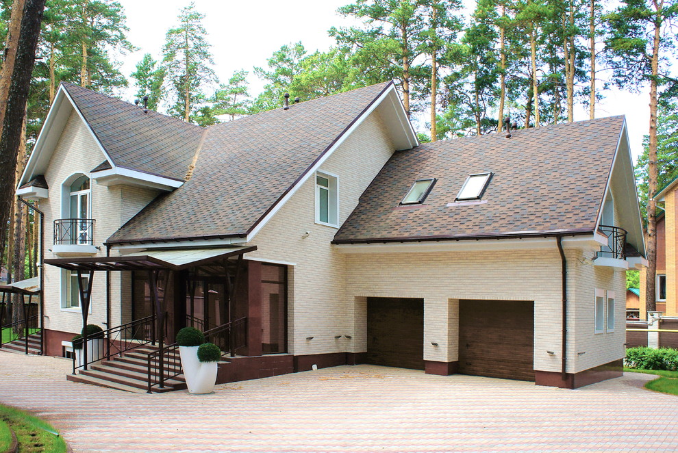 На фото: двухэтажный, бежевый частный загородный дом среднего размера в стиле неоклассика (современная классика) с комбинированной облицовкой, двускатной крышей и крышей из гибкой черепицы с