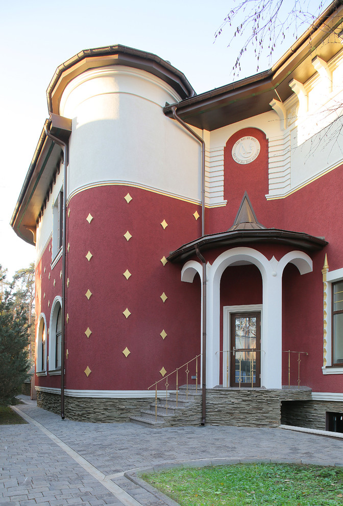 Стильный дизайн: большой, трехэтажный, красный частный загородный дом в стиле фьюжн с облицовкой из цементной штукатурки, двускатной крышей и металлической крышей - последний тренд