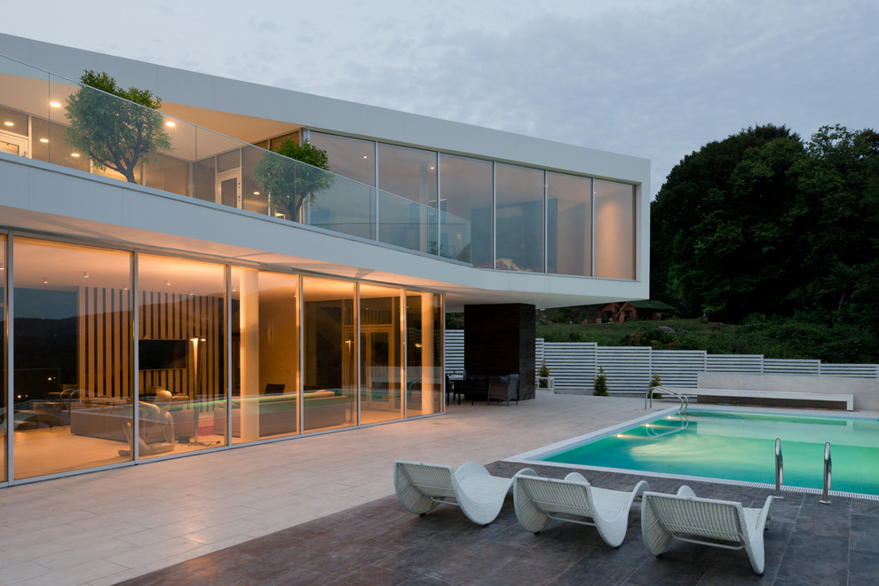 Idée de décoration pour une façade de maison blanche design en verre à un étage avec un toit plat.